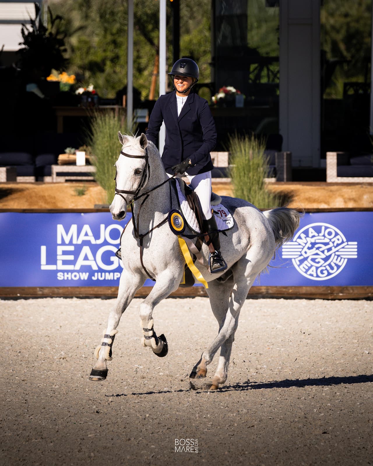 Emma Marlowe on a grey horse wearing a prize ribbon at a Major League Show Jumping event
